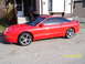 1994 Ford Probe - A red 1994 Ford Probe coupe is parked in front of a house with a trailer-like structure.