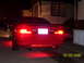 1994 Ford Probe - The rear of a red 1994 Ford Probe is visible at night with its brake lights illuminated.