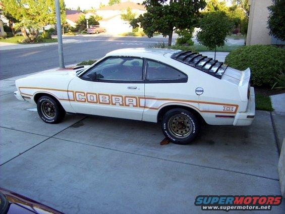 White 1977 coupe with COBRA graphics and louvers on rear window