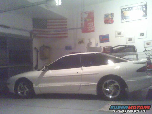White 1996 Ford Probe parked in a garage with an American flag on the wall