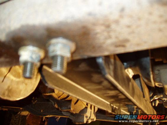 Close-up of bolts and metal brackets on a vehicle's undercarriage