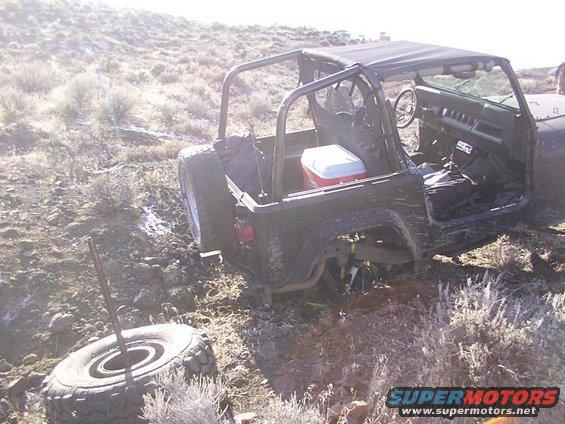 Dark SUV, possibly off-road, with front wheels in mud