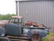 1949 Chevrolet C/K Pickup - A weathered pickup truck, likely from the late 1940s, sits loaded with debris beside a corrugated metal structure.