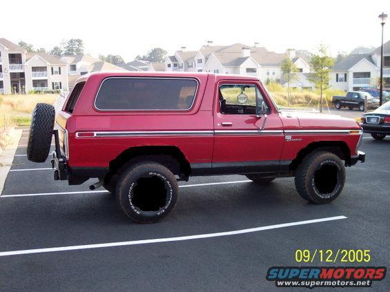 Red 1978 Ford Bronco parked in a lot, spare tire mounted on rear door