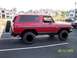 1979 Ford Bronco - Side view of a red 1978 Ford Bronco, parked in a lot with apartment buildings in the background.