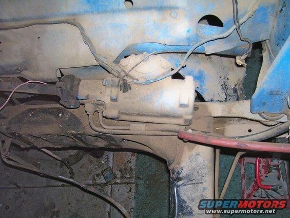 Close-up of a dirty fuel filter housing and associated lines under a vehicle
