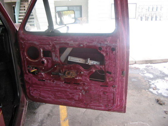 Disassembled car door interior showing window mechanism and wiring. Maroon exterior paint