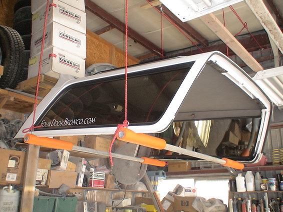 White hardtop with "FourDoorBronco.com" sticker hanging in a garage