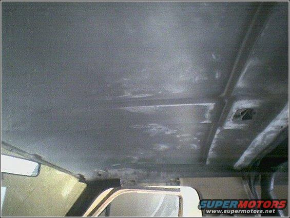 Interior ceiling of a vehicle, showing structural beams and some wear