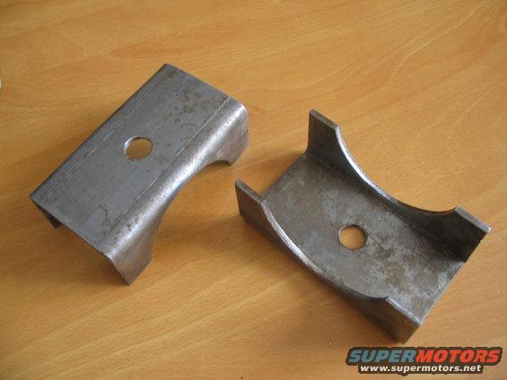 Two metal brackets with holes, one U-shaped, on a wooden surface