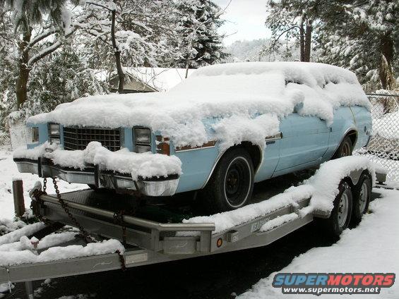 Light blue pickup truck covered in snow on a trailer