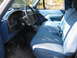 1995 Ford Bronco - The interior of a truck shows a blue bench seat and dashboard with a large steering wheel.