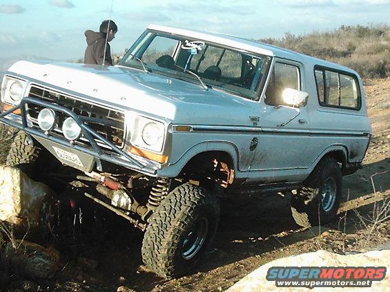 Light blue 1978 Ford Bronco with off-road modifications climbing rocks