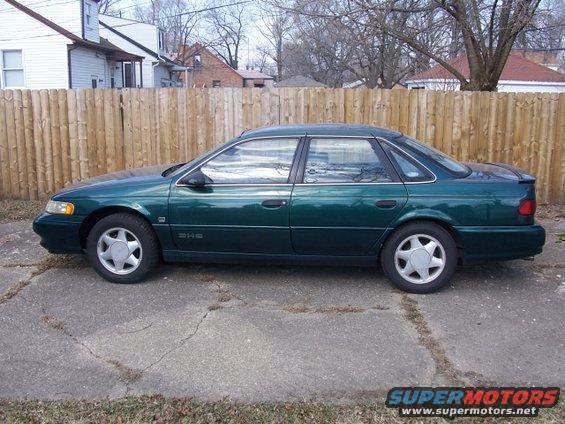1993 Ford Taurus sedan, side view, green paint, parked on cracked concrete