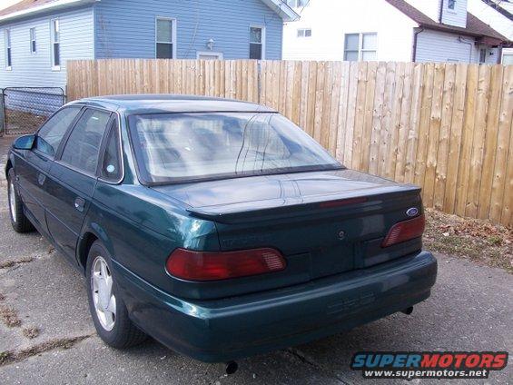 Rear view of a 1993 Ford Taurus sedan parked in front of a wooden fence