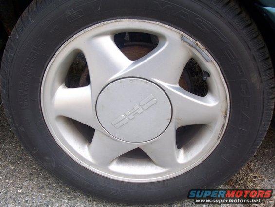 Close-up of a silver alloy wheel with a center cap displaying a stylized logo