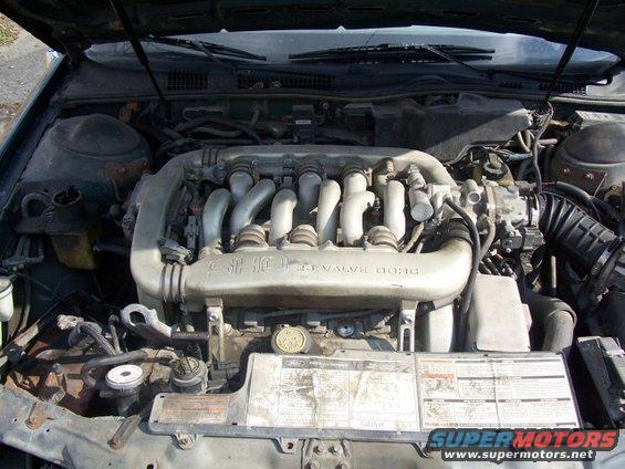Engine bay of a 1993 Ford Taurus, showing the V6 engine with intake manifold and various hoses