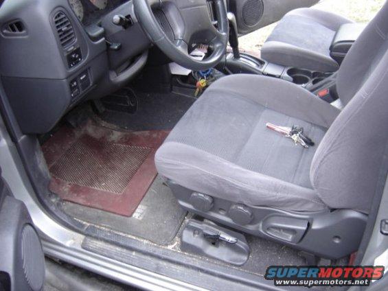 Car interior showing the driver's seat, dashboard, and steering wheel. Keys are on the seat