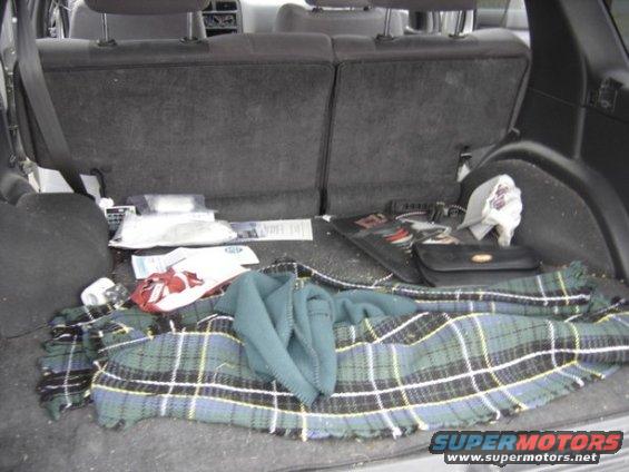 Interior cargo area with plaid blanket, bags, and purse