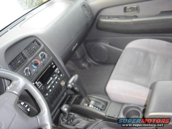 Vehicle interior showing dashboard, steering wheel, center console with gear shifter, and passenger seat