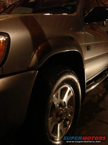 Silver SUV front fender and wheel with running boards