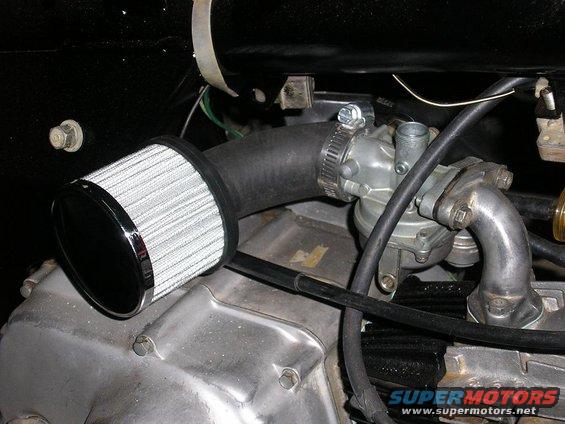 Motorcycle carburetor with chrome-ringed air filter attached to intake hose