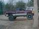 2001 Dodge 1500 - This lifted pickup truck is parked on a dirt lot with a house and trees in the background.