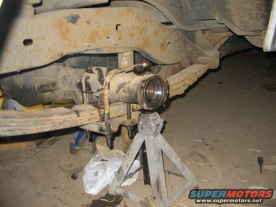 Vehicle rear axle assembly supported by jack stands, with leaf springs visible