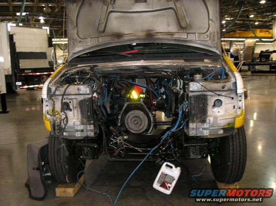 Front end of a van with hood open, engine removed, showing wiring and frame