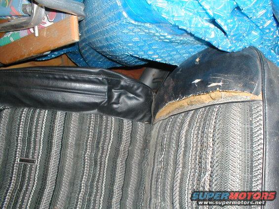 Close-up of a worn car seat with striped fabric and black vinyl trim. Some damage is visible on the vinyl