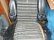 1979 Ford Bronco - Interior view of a damaged car seat with striped fabric and black vinyl trim.