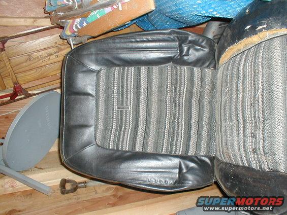 Car seat with black vinyl bolsters and striped fabric insert. Some items are stored behind it