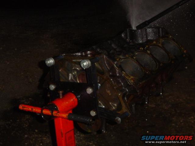 Engine block on red stand with water spraying on it