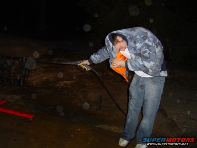 guy pressure washing an engine block outdoors at night