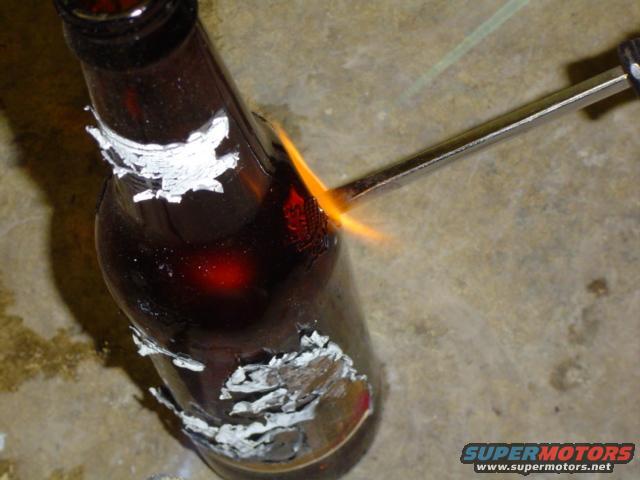 Close-up of a brown bottle with white residue being heated by a torch