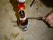 1979 Ford Bronco - A person is modifying a glass bottle using heat from a soldering iron and a screwdriver.