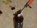 1979 Ford Bronco - A screwdriver is used to break a brown bottle on a concrete surface.