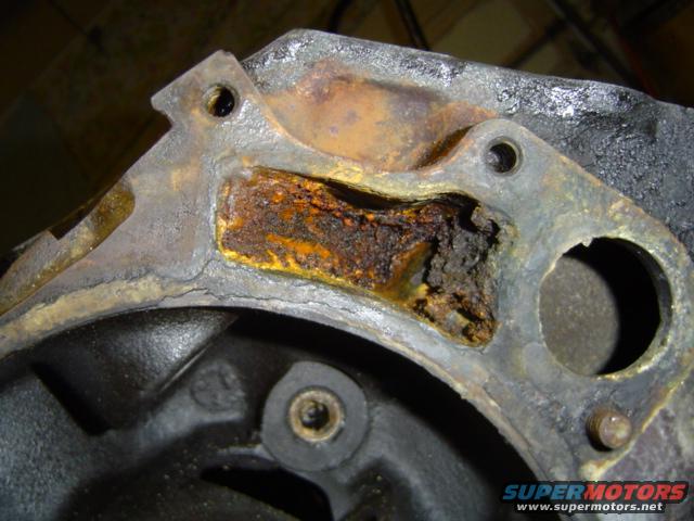 close-up of a heavily rusted engine component with a hole in it
