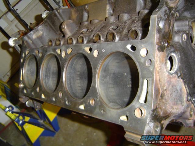 Engine block with cylinder bores visible, supported by a red engine stand