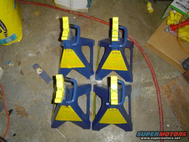 Four blue and yellow jack stands on a concrete floor