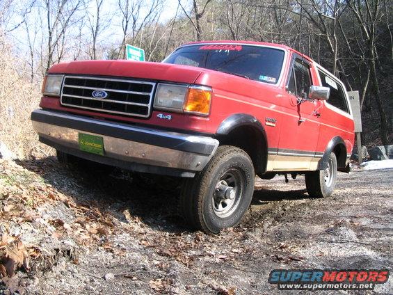 Red Ford Bronco on a dirt road, 4x4 badge visible