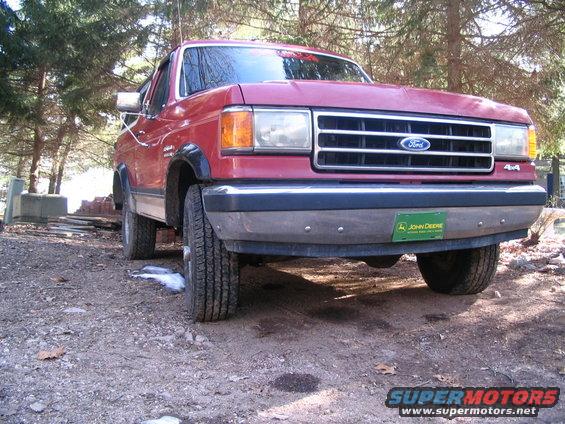 Red Ford Bronco, front view, with John Deere license plate on bumper. Appears to be late 1980s model