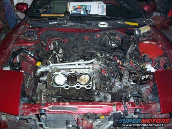 car engine bay with engine parts removed, showing cylinders and wiring