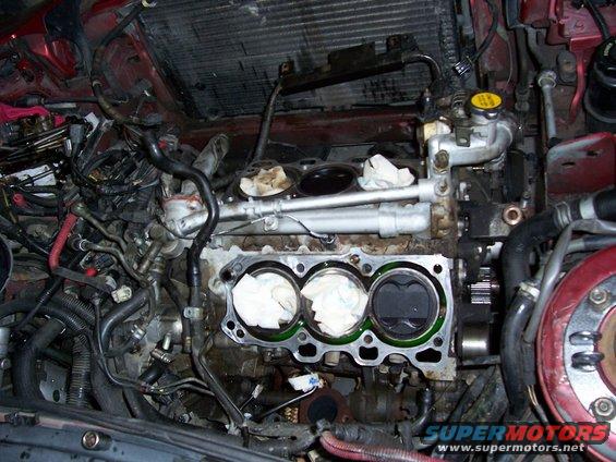 Engine bay with pistons visible, cylinder head removed. Red car interior