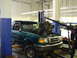 1997 Ford Ranger - A mechanic is removing the engine from a green Ford Ranger that is on a lift.