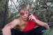 1989 Ford Bronco - A young man with visible injuries, including a black eye and bruises on his arms, sits in a wooded area while speaking on a cell phone.