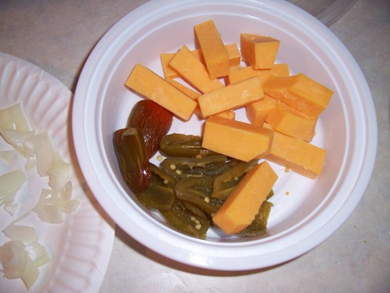 Bowl of cubed cheddar cheese and sliced jalapenos with chopped onions on a paper plate