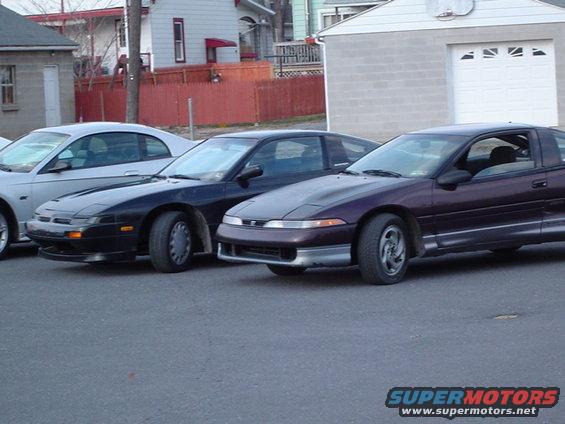 Dark purple coupe with silver trim, parked next to a black coupe and a silver coupe