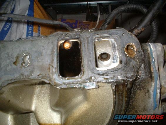 Close-up of a used engine intake manifold with gasket residue and bolt holes