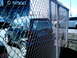1997 Ford Escort - A dark blue Smart car is parked behind a chain-link fence, with a white SUV in the background.